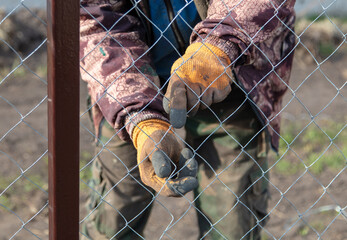 A man sets a metal mesh on the fence.
