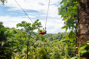 Fototapeta premium Young male tourist swinging on the cliff in the jungle