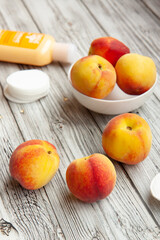 Naklejka na ściany i meble Personal care, cosmetics, cream of peach, ripe peaches, cotton balls for the face on a light wooden background