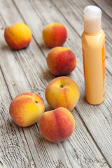 Personal care, cosmetics, cream of peach, ripe peaches, cotton balls for the face on a light wooden background