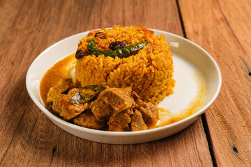 Indian Mutton Biryani Dish served on wooden table. Typical food from India, made from goat meat mixed with spices and basmati rice