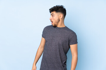 Arabian handsome man over isolated background doing surprise gesture while looking to the side