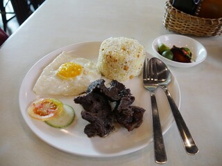 A favorite Filipino breakfast of “Tapsilog” ( beef tapa, singangag and itlog) dried cured beef, fried rice and fried egg, with lemon and peppers