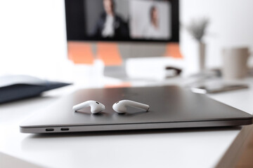 Smartphone with video call and headphones on a gray Desktop. Top view.