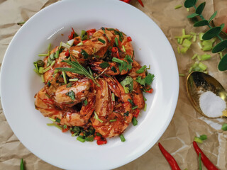 Stir Fried Prawns with Salt,garlic and Chili in white dish on Brown paper background