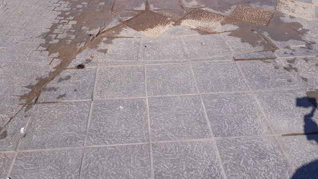 Stone floor wet by the water of a fountain on the promenade of Lake Chapala with boats, entrance pier, viewpoint and mountains in the background, sunny day in Jalisco, Mexico