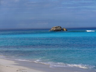 A beautiful rock formation breaks the vast blue of the waters in a tropical beach