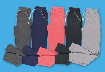 Folded multi-colored jogging pants. Set. Blue background.