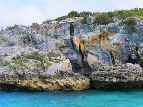 Close up of the rocky cliffs at the Thunderball Grotto in the blue waters of Exuma Cays, Bahamas. The location is a popular destination and has been used for filming several movies.