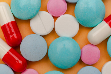 Close up of pills on orange background, concept of painkillers addiction. Lot of tablets, overdose.