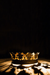 Vertical photo for posters and banners. A crown on a black background is highlighted with a golden...