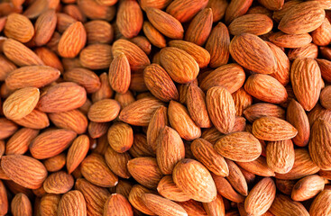 Peeled almond pieces/stack bulk. Food and background photo, selective focus on top surface.