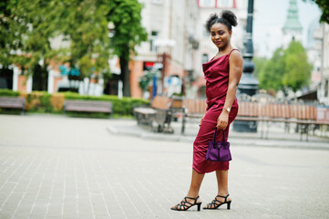 Portrait of a beautiful natural young African woman with afro hair. Black model in red silk dress.