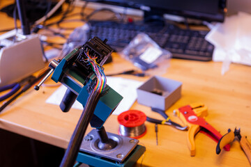 Closeup image of soldering station with colored electrical cables and wires in a vice machine
