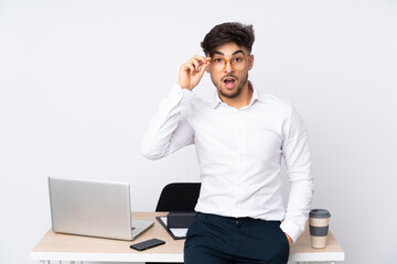 Arabian man in a office isolated on white background with glasses and surprised