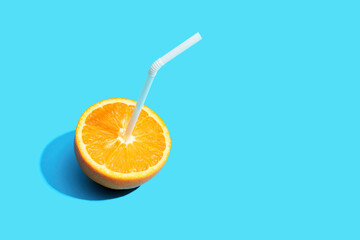 Fresh orange fruit with straw on blue background