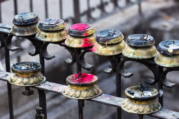 Buddhist butter lamps on a railing with red powder in Swayambhunath, Kathmandu, Nepal