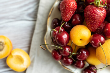 fresh fruits and berries in a plate on a light background