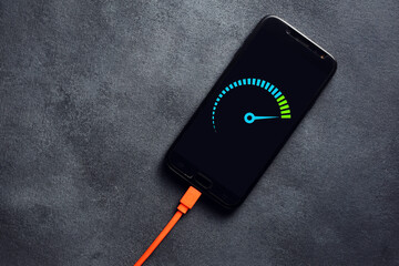 Smartphone connected to a usb charging cable and fast charging on black background