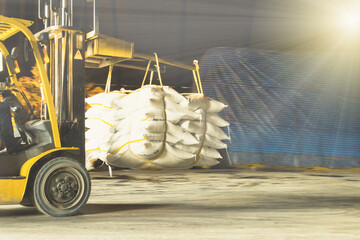 Forklift carries jumbo bag of refine white sugar to put on the stack inside warehouse. Sugar warehouse operations and management.