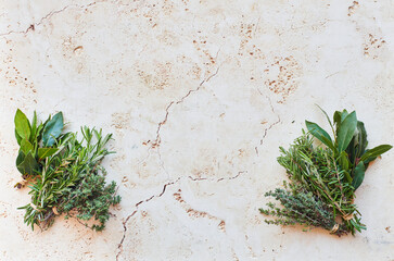 Travertine background with fresh herbs in corners and copy space