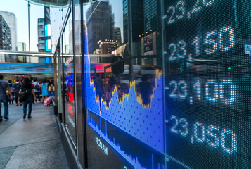 Display of Stock market quotes with city lights reflect on glass