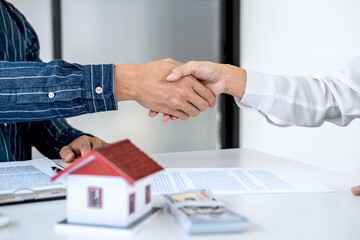 Real estate agent and customers shaking hands together celebrating finished contract after signing...