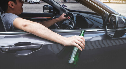 Close up of bottle, Young asian man drives a car with drunk a bottle of beer behind the wheel of a car