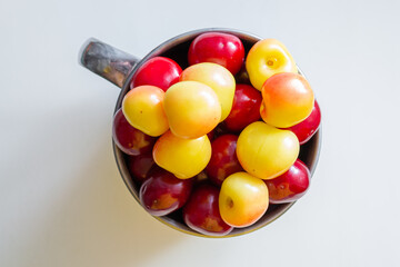 Sweet cherries in a steel mug on a white paper background