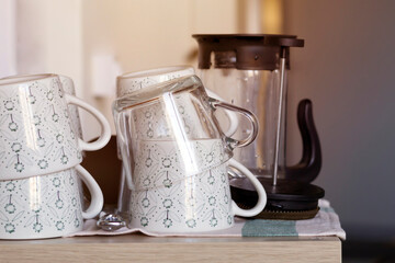 Clean tea cups and teapot on the tablecloth on wooden table with sunlight, toned, close-up. Party, tableware concept. Copy space