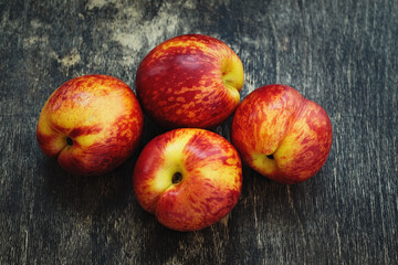 Four nectarines lie on a brown wooden floor. View from above