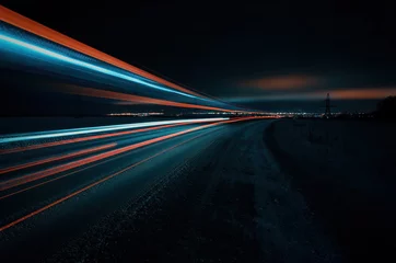 Foto op Plexiglas Zwart Lange blootstelling van een weg met lichte sporen van passerende voertuigen, gloeiende lucht