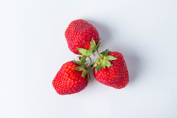 Strawberries on a white background. Three red, ripe and juicy strawberries. Strawberries are ponytails with each other