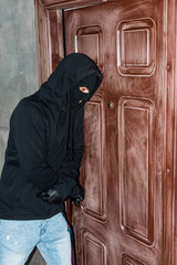 Burglar in mask breaking door lock with screwdriver