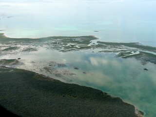 Wide aerial shot of some of the islands of the Exuma Cays surrounded by clear blue waters of the Bahamas