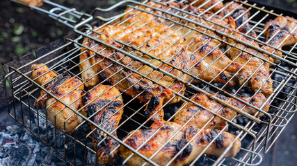 The process of frying chicken meat on the grid a barbecue in the backyard.