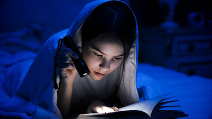 Portrait of teenage girl reading book in bed with flashlight - obrazy, fototapety, plakaty