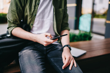 Fototapeta premium Thoughtful hipster guy updating profile on telephone device using high speed internet connection