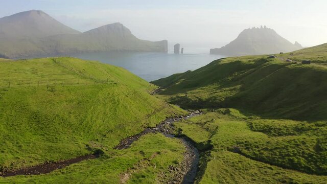Colorful summer scene of Faroe Islands with Tindholmur cliffs on background, Vagar island, Denmark, Europe. Sunny morning seascape of Atlantic ocean. 4k drone footage (Ultra High Definition).