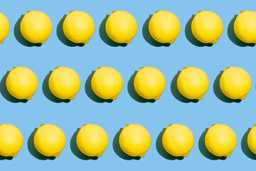Repeating seamless photo pattern of fresh whole yellow lemons on blue background. Food texture