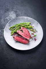 Barbecue dry aged wagyu rib-eye beef steak with green asparagus and red wine salt as closeup on a modern design plate with copy space