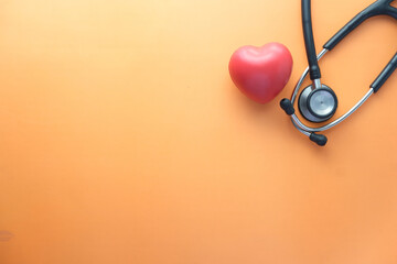 heart shape symbol and stethoscope on orange background 