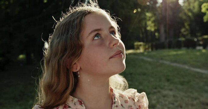 Young girl looking gazing at the sun in parkland