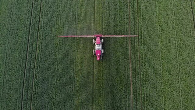 Aerial view of the tractor that irrigates the green field. Chemical treatment of the field with pesticides and protection against insects of rodents, parasites and pests