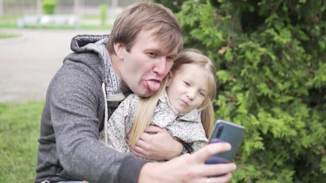 Dad takes a selfie photo on a mobile phone with a beautiful little daughter.