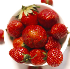 Fresh red strawberries in a bowl on white background close up.