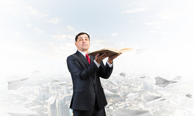 Serious businessman holding open old book