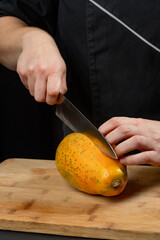 woman hands cutting papaya on a wood cut board with a knife