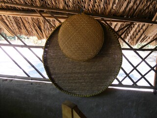 Pair of big and small winnowing baskets hanging from a nail in an open outdoor kitchen. These are used to separate the grains from the chaffs.