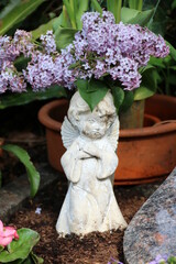  Fliederbl&uuml;ten neben Friedhofsengel auf einem Grab